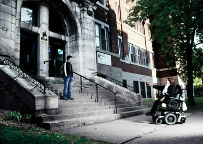Un jeune garçon devant son école accueilli par une femme en fauteuil roulant