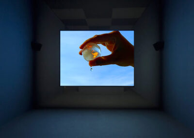 Projection montrant une main tenant une boulette d'eau représentant la Terre en feu