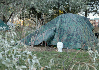 Une tête sculptée devant une tente à motifs camo