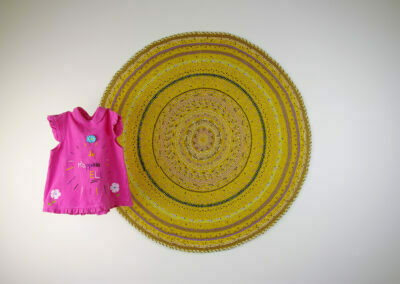 Une robe de bébé rose devant une mandala jaune